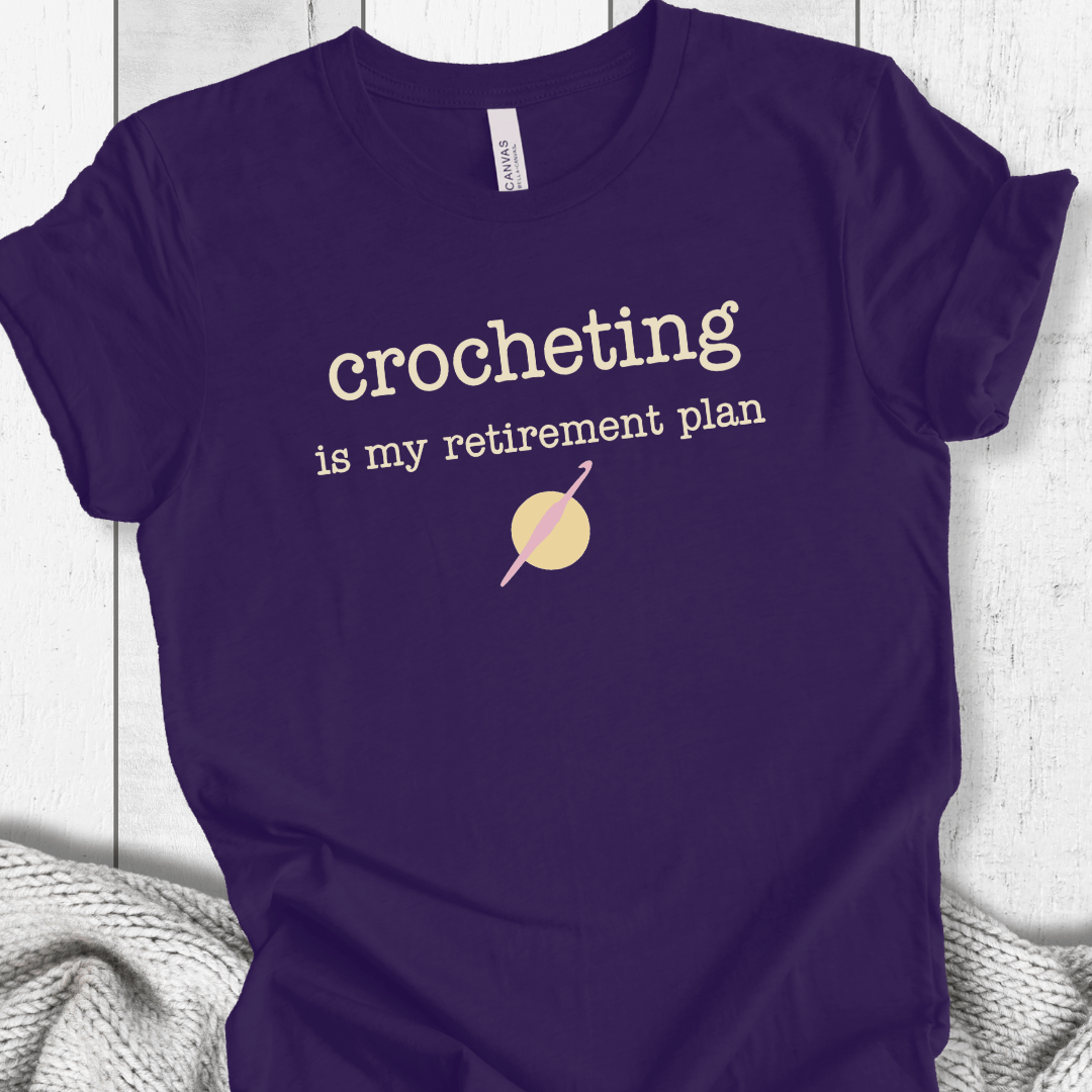 Navy blue t-shirt with 'crocheting is my retirement plan' text, perfect for crochet enthusiasts.