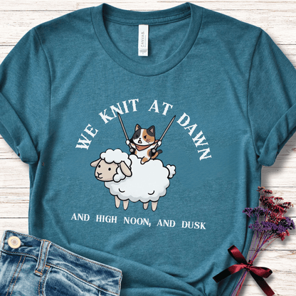 Teal cotton t-shirt with a cute graphic of a cat knitting on a sheep, perfect for knitters and cat lovers.