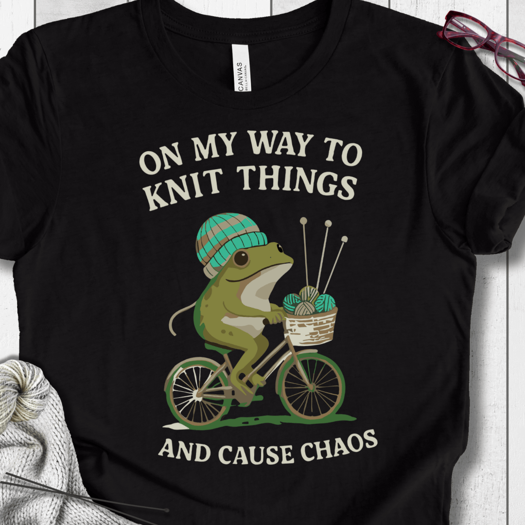 Funny black t-shirt featuring a frog on a bicycle with a knitting theme.