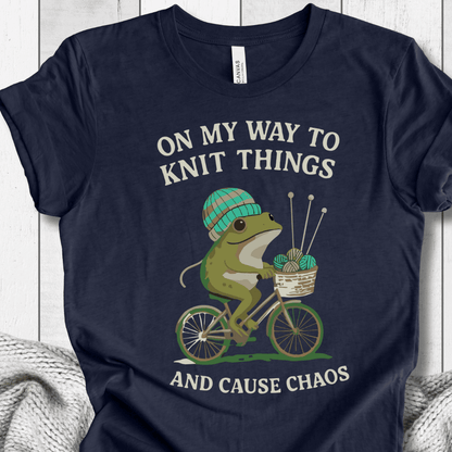 Navy blue shirt featuring a fun frog graphic riding a bike, with knitting accessories and text humor.