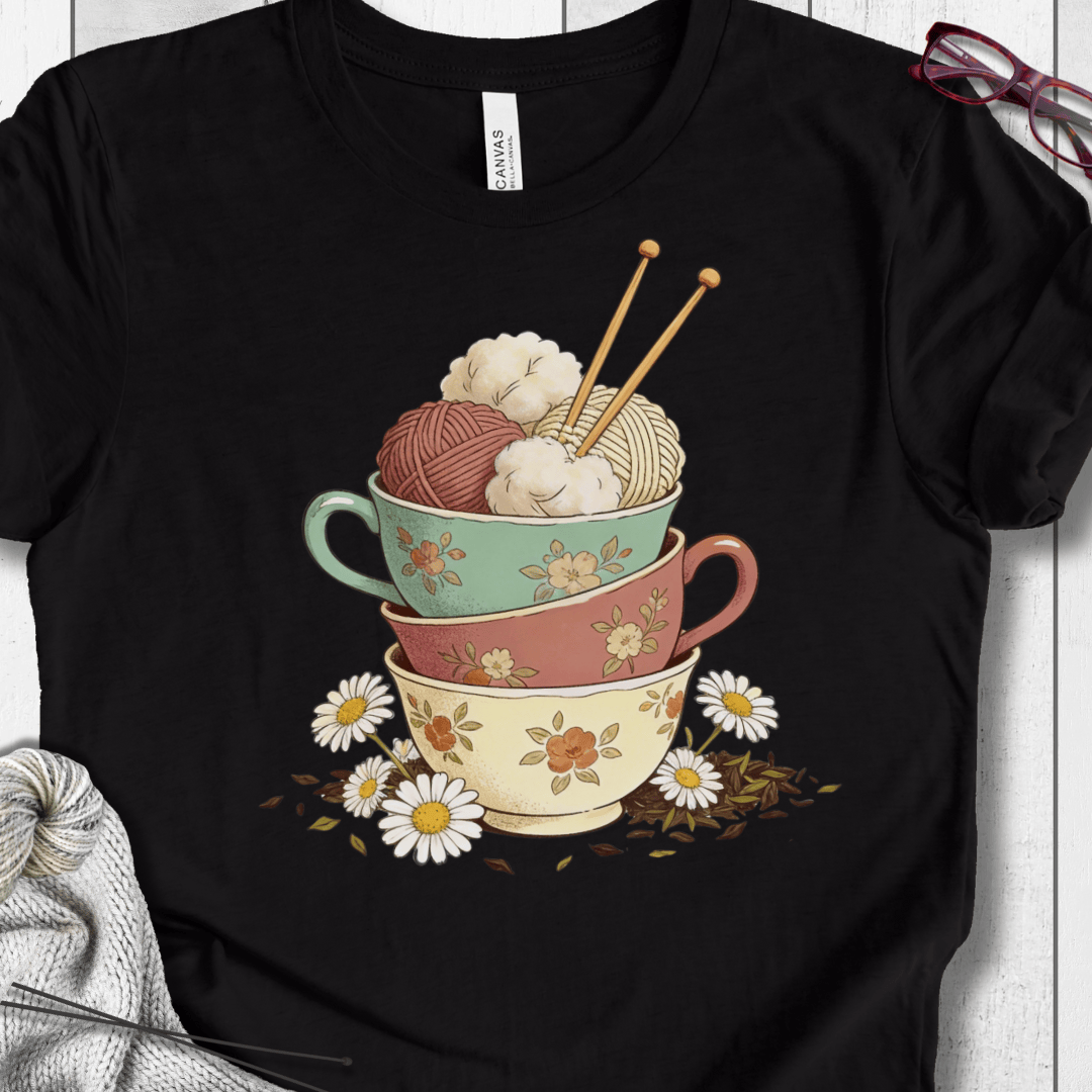 Black t-shirt featuring colorful stacked teacups with yarn and flowers, perfect for craft lovers.