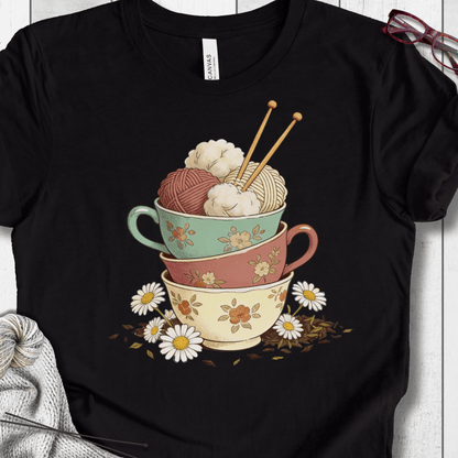 Black t-shirt featuring colorful stacked teacups with yarn and flowers, perfect for craft lovers.