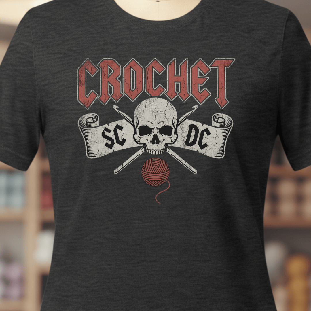 Dark gray crochet-themed t-shirt featuring a skull, yarn, and crochet hooks design.
