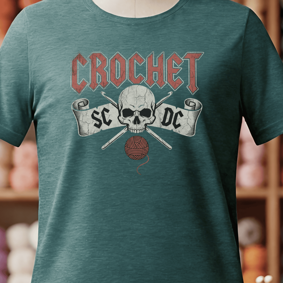 Teal crochet t-shirt featuring skull graphic and knitting tools, perfect for craft enthusiasts.