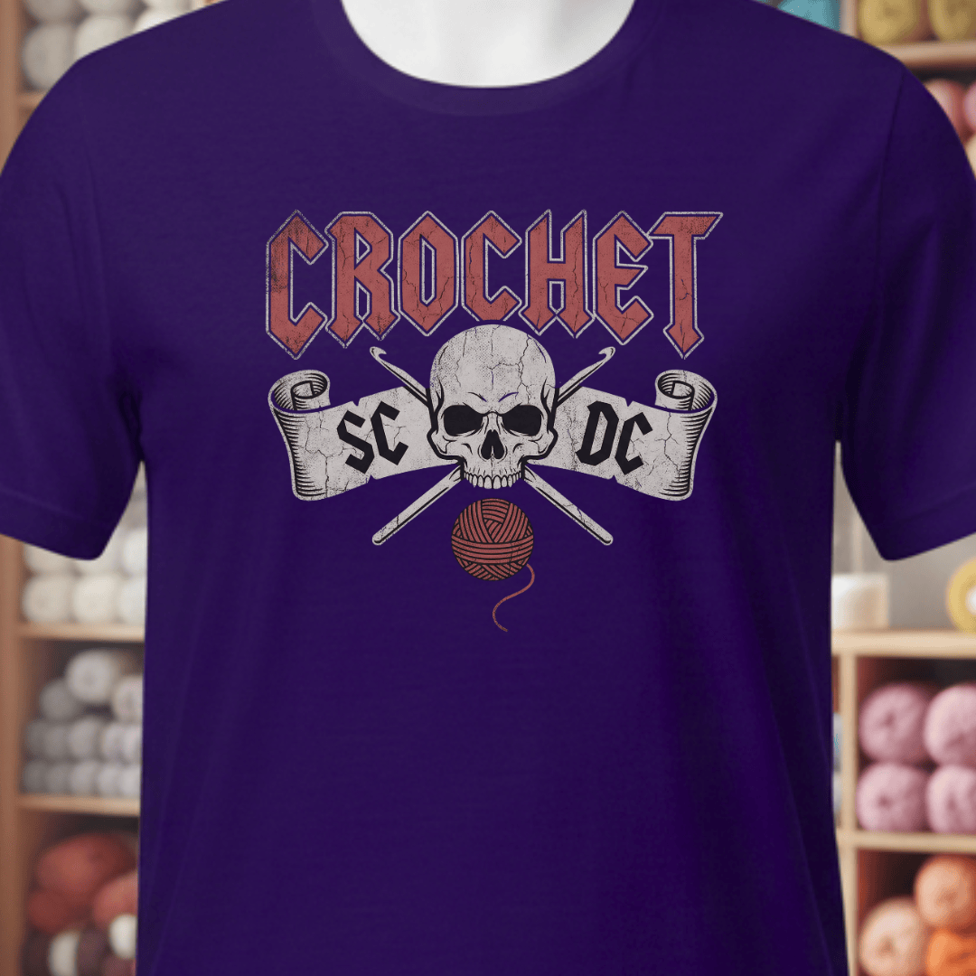 Purple crochet-themed t-shirt featuring a skull, crossbones, and yarn ball design.
