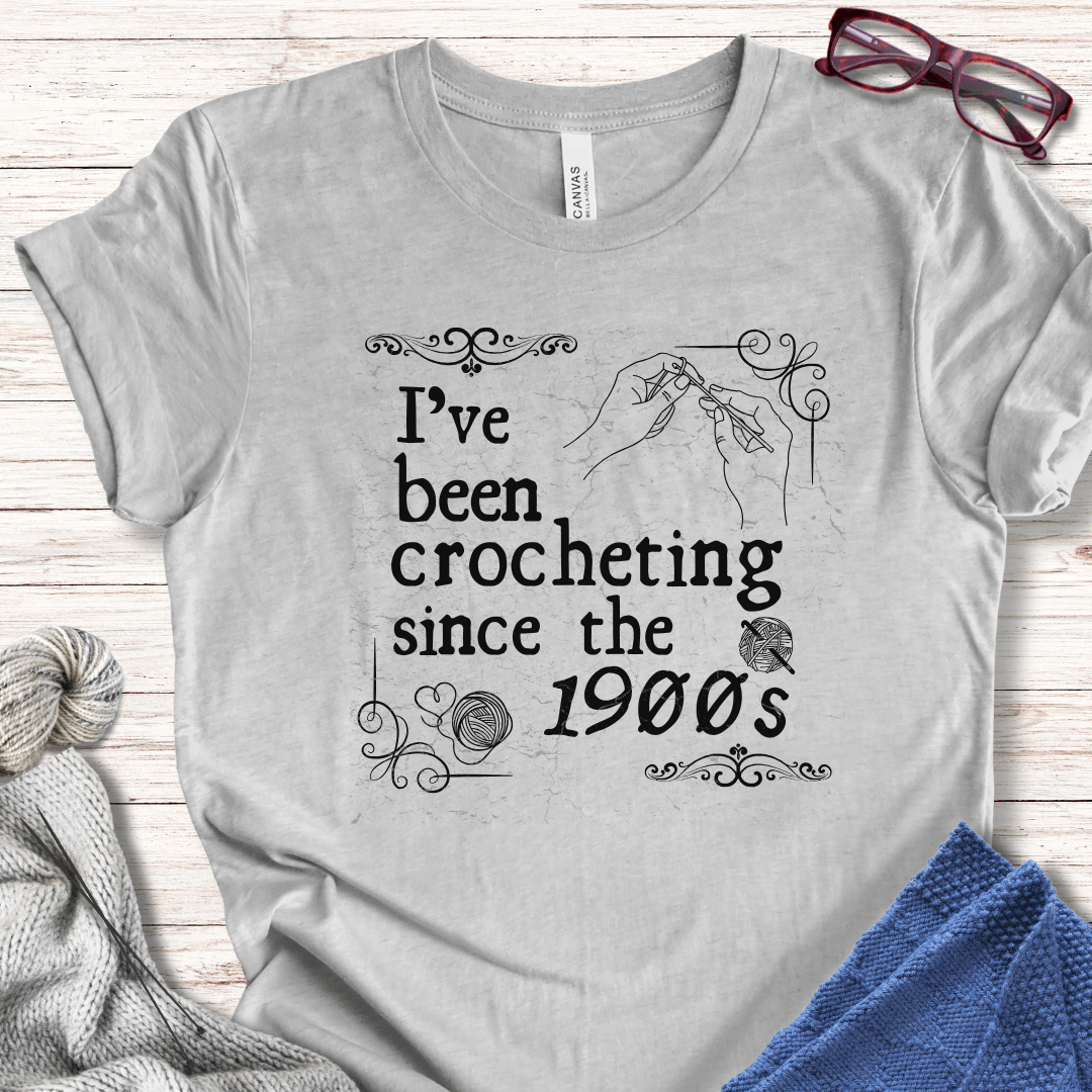 Light gray t-shirt with 'I've been crocheting since the 1900s' design, perfect for crochet enthusiasts.