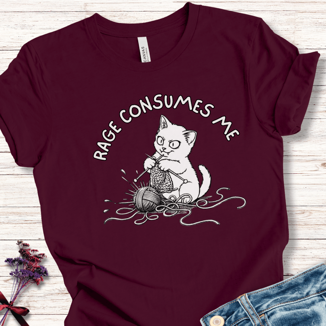 Maroon t-shirt featuring a cartoon cat knitting with yarn, text reads 'RAGE CONSUMES ME'