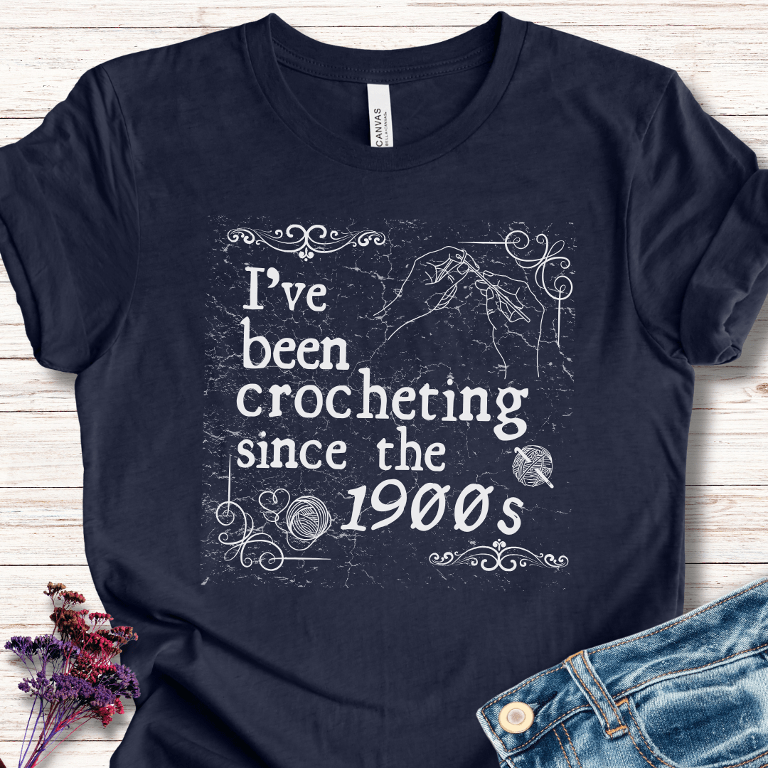 Navy blue t-shirt with 'I've been crocheting since the 1900s' graphic, made for crochet enthusiasts.