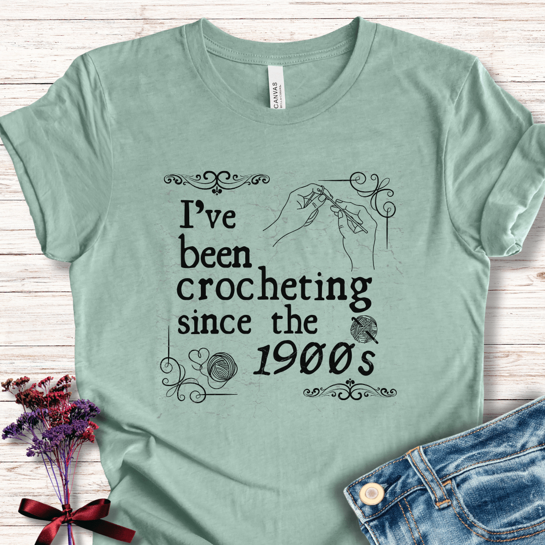 Mint green crochet-themed t-shirt with vintage design and text 'I've been crocheting since the 1900s'.